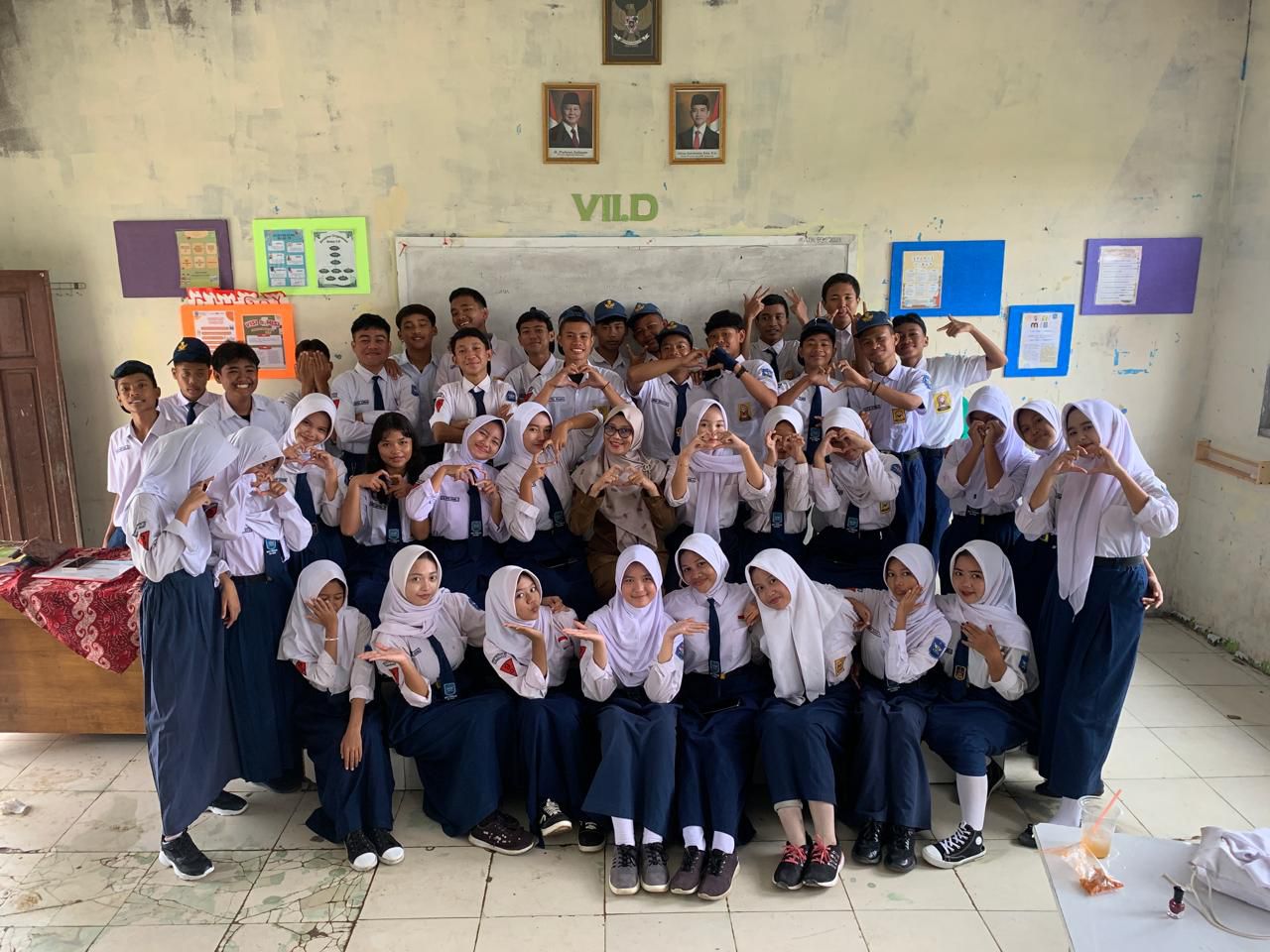 Background hero image showing a beautiful school campus with students of SMPN2 Tarumajaya in class 9D celebrating their farewell